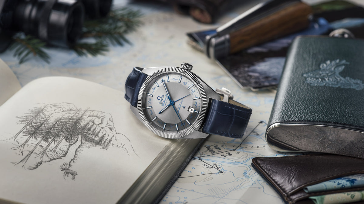 Omega Globemaster Watch with blue strap on a map with a pen and leather case